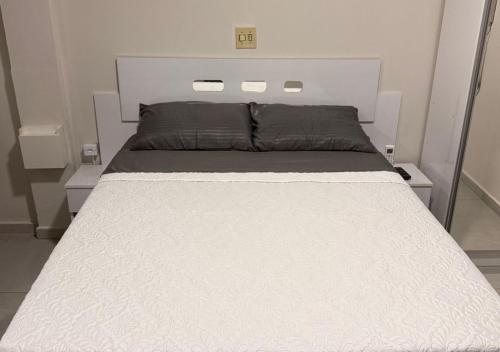 a large white bed in a small room at Quitinete Inteligente no Centro Da cidade Unidade 02 in Presidente Prudente