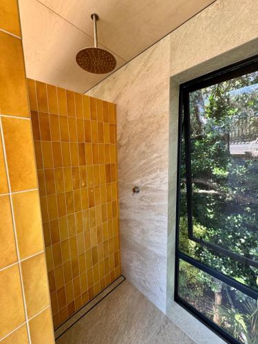 a bathroom with a shower with a large window at Waiheke Horizons Palm Beach in Waiheke Island