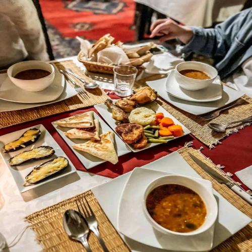 einen Tisch mit Teller mit Speisen und Schalen mit Suppe in der Unterkunft Desert Nomads Camp in Merzouga