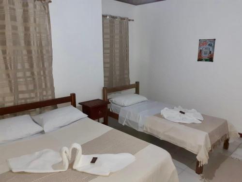 two beds in a room with white towels on them at Bromelias Imbassai in Imbassai