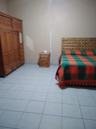 a bedroom with a bed and a cabinet and a tiled floor at Casa Ana Liz in Oaxaca City