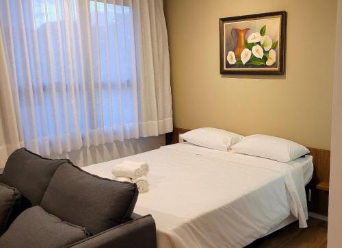 a bedroom with a bed and a couch and a window at Blend Coliving One - 2b in Ribeirão Preto