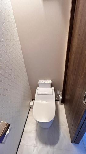 a bathroom with a toilet and a wooden door at HiL town yamanashi 26 LIAN in Kofu