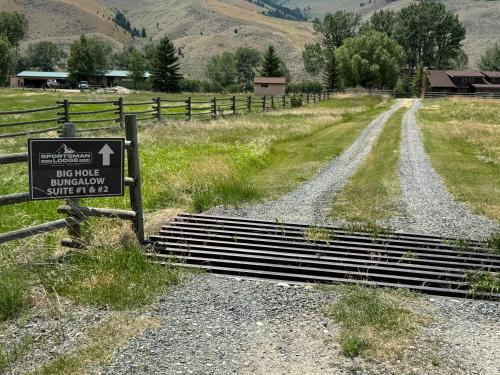 a sign on a dirt road next to a fence at Sportsman Lodge Melrose MT in Melrose