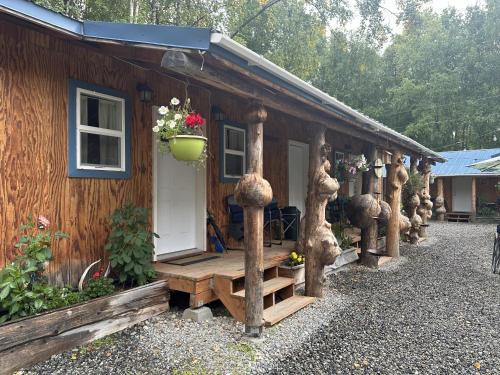 a wooden cabin with a porch with a bench and flowers at talkeetna villas and tours in Talkeetna