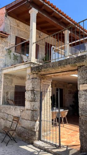 a stone house with a balcony and a chair at Casa María da Reza in Ribadavia