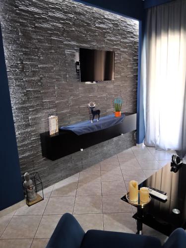 a living room with a tv on a brick wall at Maka's Design Suite-Trikala in Tríkala