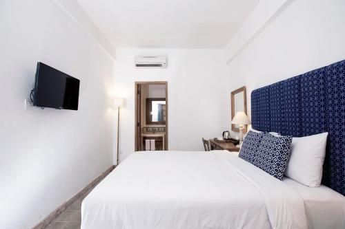 a white bedroom with a bed and a tv at Adhisthana Hotel Yogyakarta in Yogyakarta