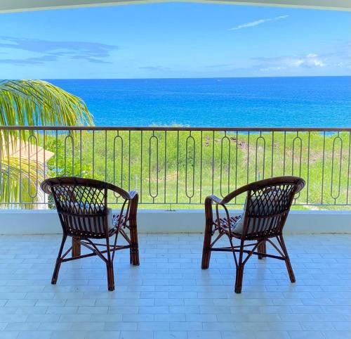 two chairs on a balcony looking out at the ocean at Cosy Escape in Flic-en-Flac