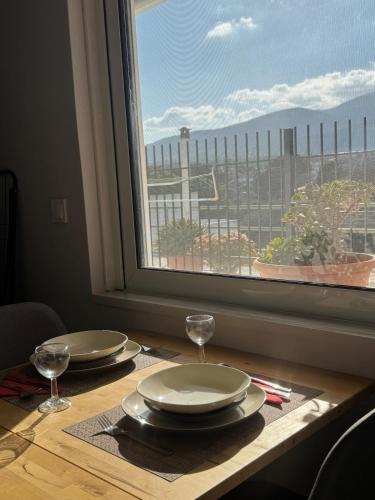 a table with plates and wine glasses and a window at HalCyon-On the blue in Nea Makri