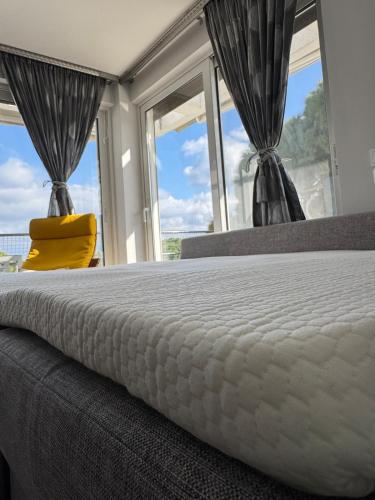a bedroom with a bed with a yellow pillow and windows at HalCyon-On the blue in Nea Makri