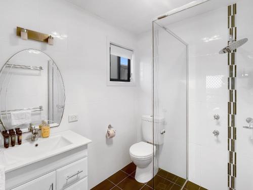 a white bathroom with a toilet and a shower at Coastal Upper-Level Home with Shared Pool Access in Batehaven