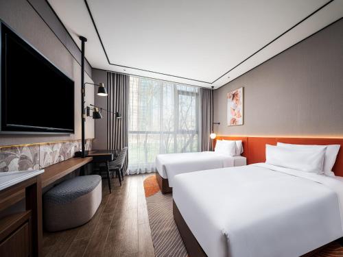 a hotel room with two beds and a flat screen tv at Hilton Garden Inn Beijing Guomao in Beijing