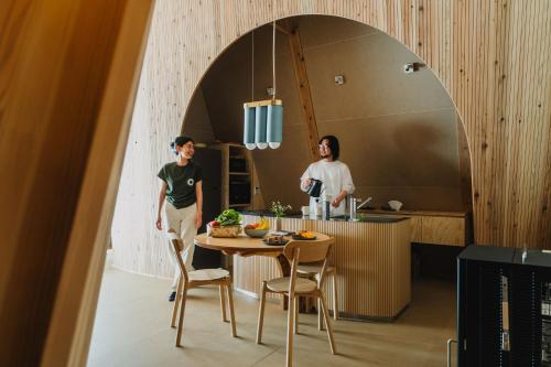 two people standing in a kitchen with a table at SANU 2nd Home 那須2nd in Nasu