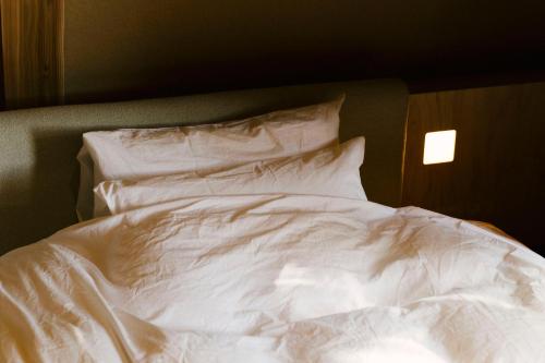 an unmade bed with white sheets and pillows at SANU 2nd Home 那須2nd in Nasu