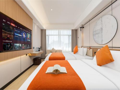 a hotel room with two beds and a flat screen tv at Jiuquan Smart Hotel in Jiuquan