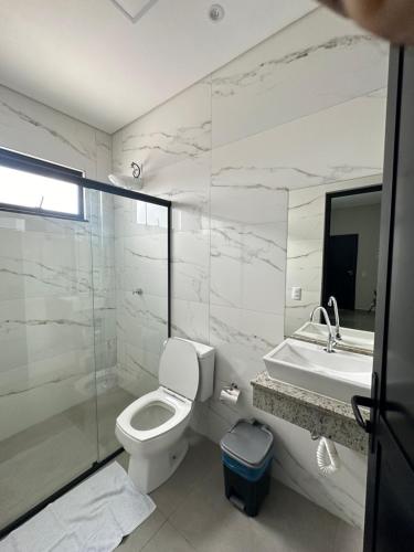 a white bathroom with a toilet and a sink at LAR Espaço Lazer in Foz do Iguaçu