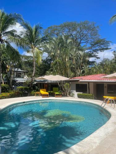 a swimming pool with two chairs and a house at Parti Gras Hotel & Villas en Playa Potrero in Potrero