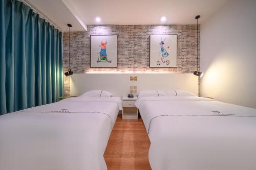 three beds in a room with green curtains at QiQiaoWu Fashion Hotel - Beijing Songjiazhuang Subway Station in Beijing