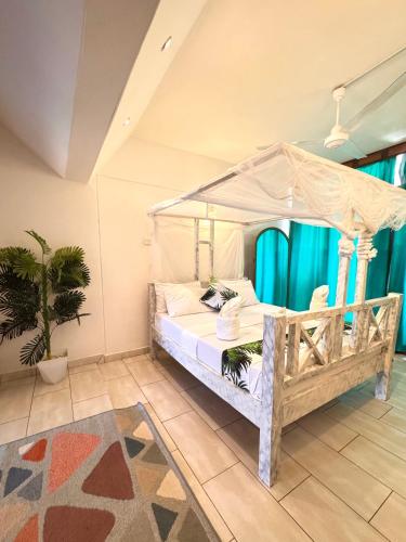 a bedroom with a canopy bed and a potted plant at Bahari Studio Beach Front Apartment. in Diani Beach