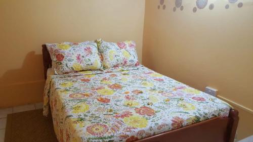 a bedroom with a bed with a floral bedspread and pillows at Faith & Peace Guest House in Fontenoy