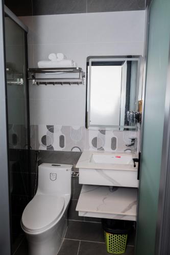 a bathroom with a toilet and a sink and a mirror at Suka Hotel in Tây Ninh