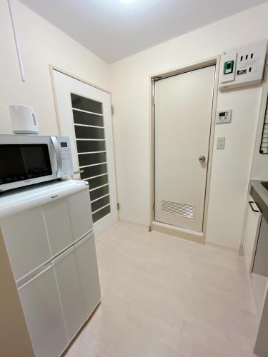 a white kitchen with a microwave and a door at ToyamaHouse2-203 in Tokyo