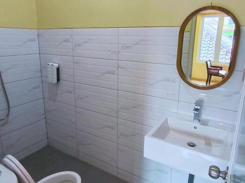 a white bathroom with a sink and a mirror at Pomah Guesthouse in Jatingaleh