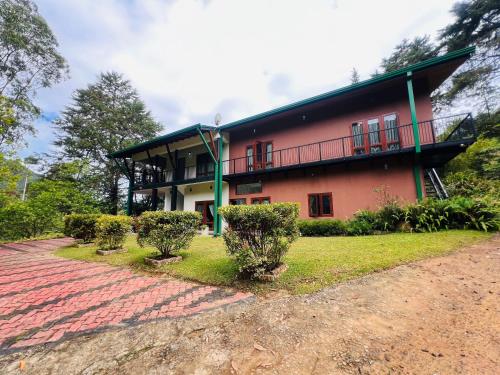 a red building with a balcony and bushes in front of it at Agarapathana Estate Holiday Bungalow in Hatton