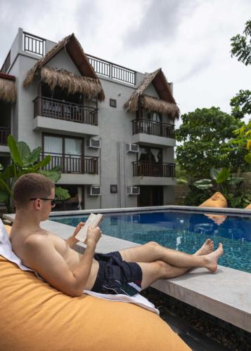 a man laying on a raft reading a book next to a swimming pool at Asgard Resort & MMA Gym in General Luna