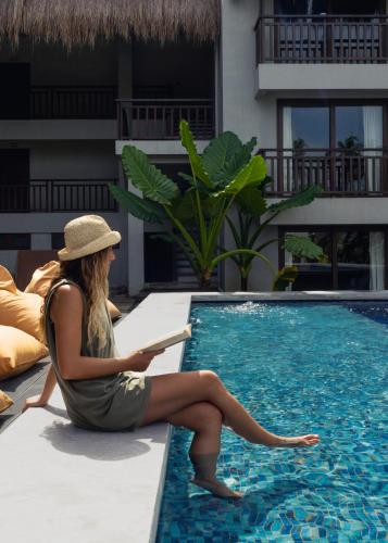 a woman in a hat sitting next to a swimming pool at Asgard Resort & MMA Gym in General Luna