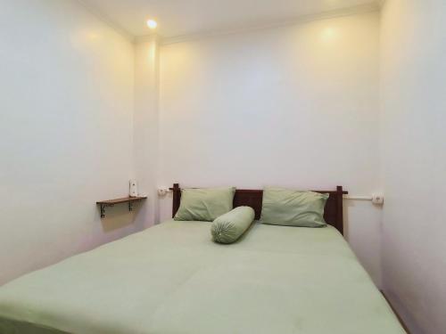 a small bedroom with a bed with green sheets and pillows at Pomah Guesthouse in Jatingaleh