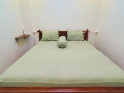 a bed with green sheets and a pillow on it at Pomah Guesthouse in Jatingaleh
