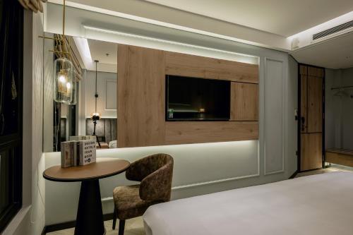a bedroom with a bed and a table and chair at iRest Signature Ba Dinh Lakeside in Hanoi