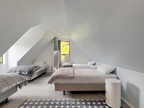 a white bedroom with two beds and a window at 6 Beds 2 Bathrooms Private Holiday Home in Akaroa