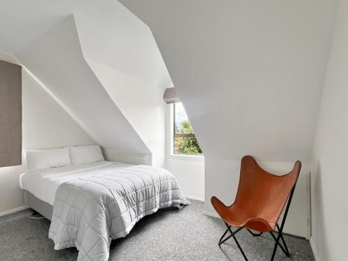 a white bedroom with a bed and a chair at 6 Beds 2 Bathrooms Private Holiday Home in Akaroa