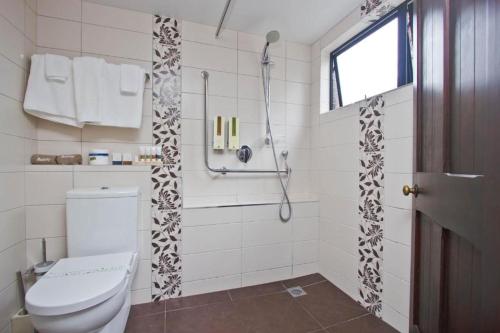 a white bathroom with a toilet and a shower at Knights Inn in Auckland