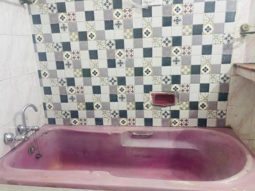 a pink bath tub in a bathroom with a tiled wall at Radha Madhavam Luxurious Boutique Stay in Mathura