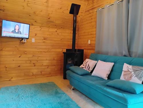 a living room with a blue couch and a flat screen tv at Cabanas Pôr do Sol - São Chico in São Francisco de Paula