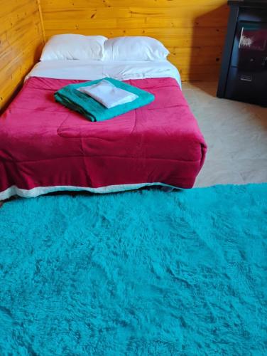 a bed with a red blanket and a blue rug at Cabanas Pôr do Sol - São Chico in São Francisco de Paula