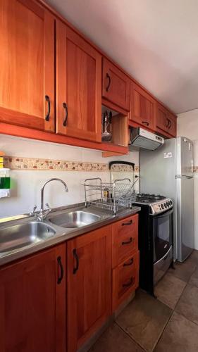 a kitchen with wooden cabinets and a sink and a stove at Cabaña Sol Nevado, Las Trancas in Las Trancas
