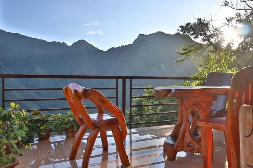 a wooden table and chairs on a balcony with mountains at Batad Pension and Restaurant in Banaue