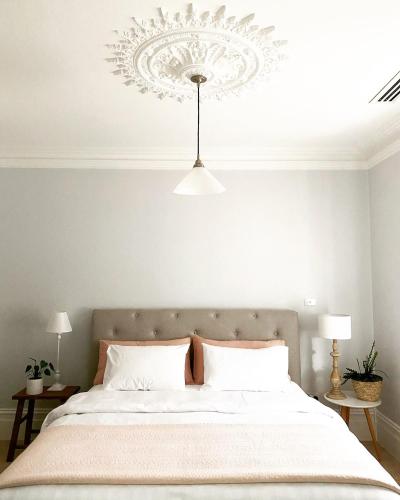 a bedroom with a large bed with a chandelier at Saint Brides - Steps to Pako in Geelong West