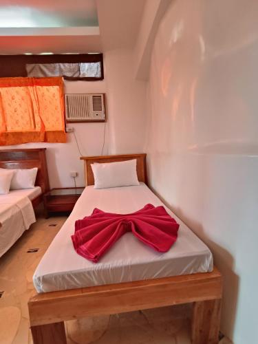 a bed with a red bow tie on it at Casa de Arte in Boracay