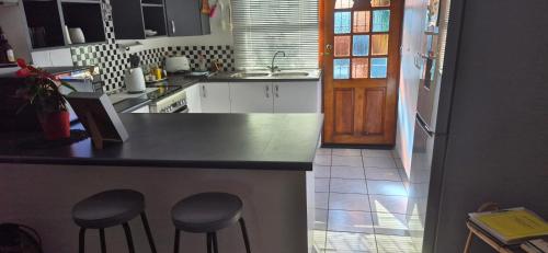 a kitchen with a counter and two stools in it at At lilac, Jeffreys Bay, cottage for 2 in Jeffreys Bay