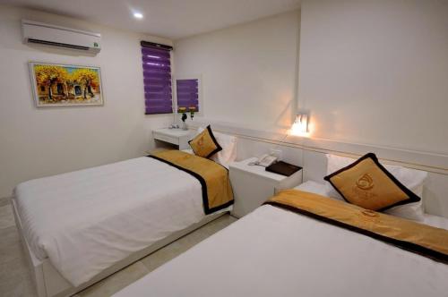 a hotel room with two beds and a sink at Yellow Sea Hotel Nha Trang in Nha Trang