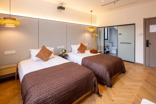 a hotel room with two beds and a bathroom at Wuzhen Xizha Slow Life Riverside Inn in Wujiaqiao