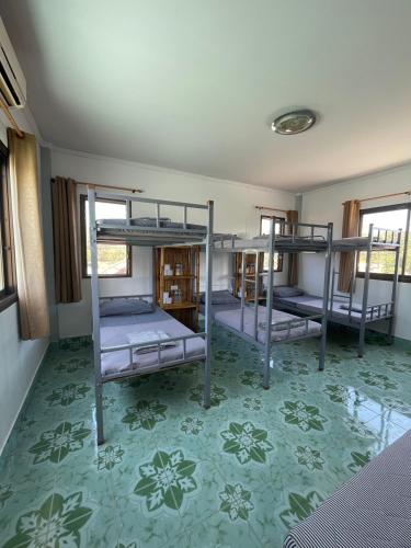 three bunk beds in a room with a green floor at Lanta Corsica Hostel in Ko Lanta Yai