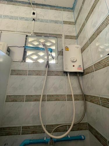 a bathroom with a hose on a tiled wall at Lanta Corsica Hostel in Ko Lanta Yai