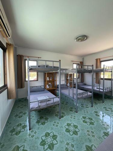 three bunk beds in a room with a green floor at Lanta Corsica Hostel in Ko Lanta Yai